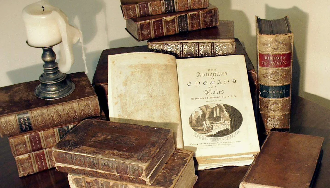 An open antiquarian volume among old books, with a candle at one side